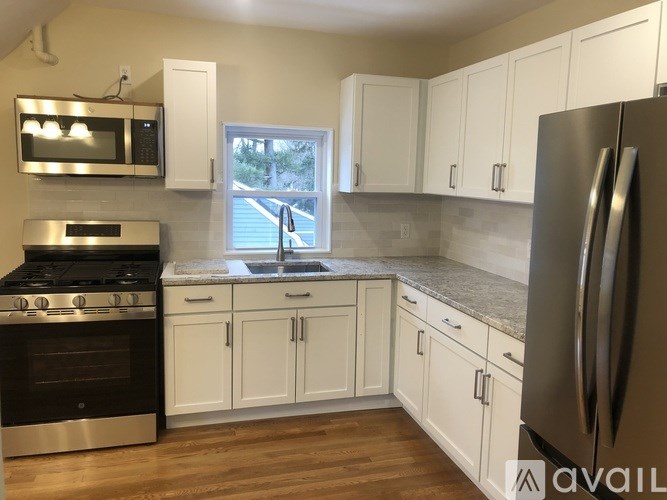 A kitchen with white cabinets and a stainless steel refrigerator.