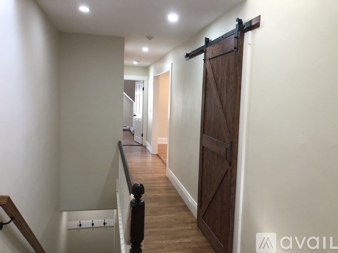 A hallway with a wooden door and a black railing.