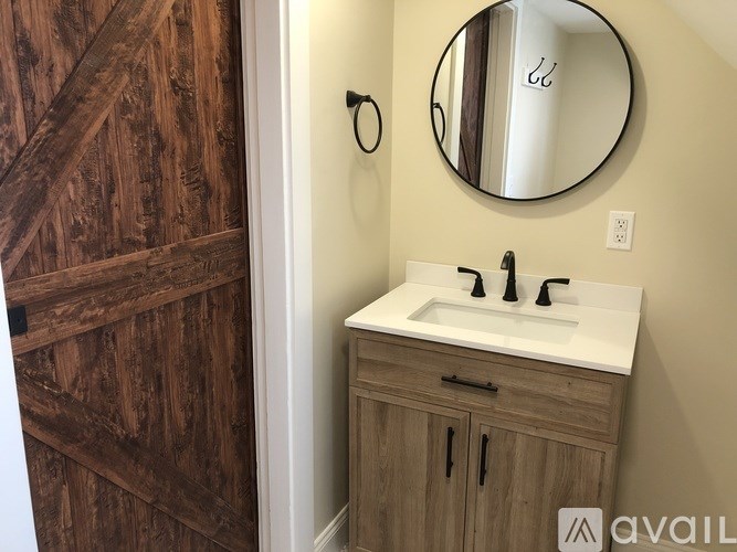 A bathroom with a white sink and a round mirror above it.