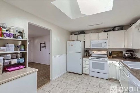 A kitchen with white appliances and a skylight.