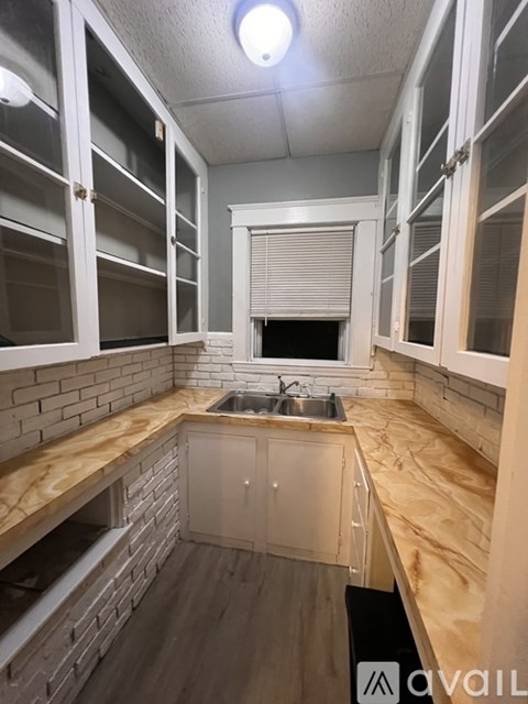 A kitchen with wooden cabinets and a brick wall backsplash.