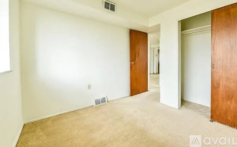 A room with a carpeted floor and two doors.