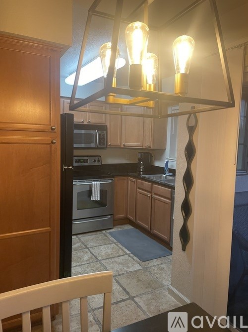 A kitchen with a microwave, oven, and a hanging light fixture.