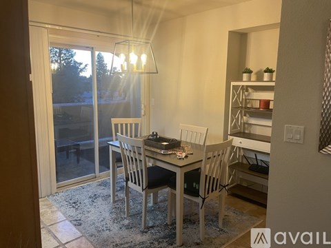 A dining room with a table and chairs and a view of the backyard through a sliding glass door.