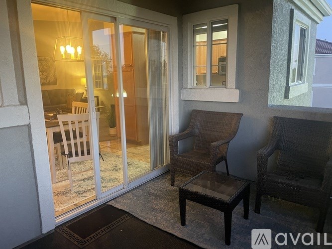 A patio with a table, two chairs and a glass door.
