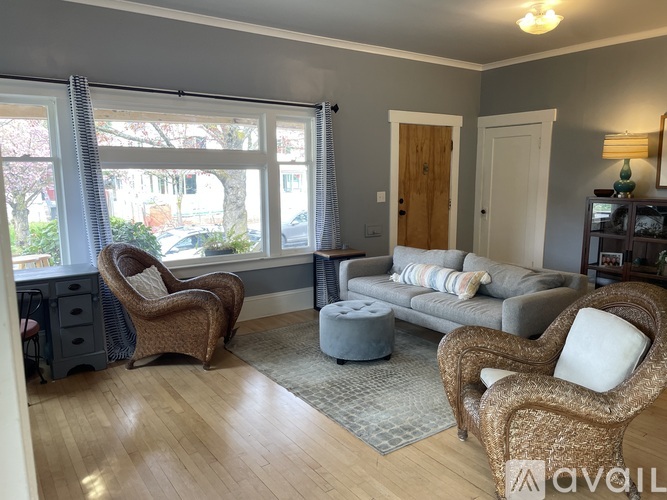 A living room with a grey couch, two chairs and a small ottoman.