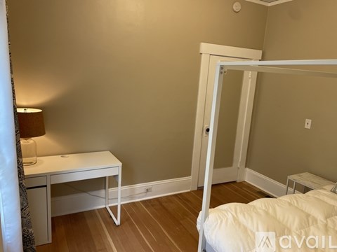A bedroom with a white bed and desk.