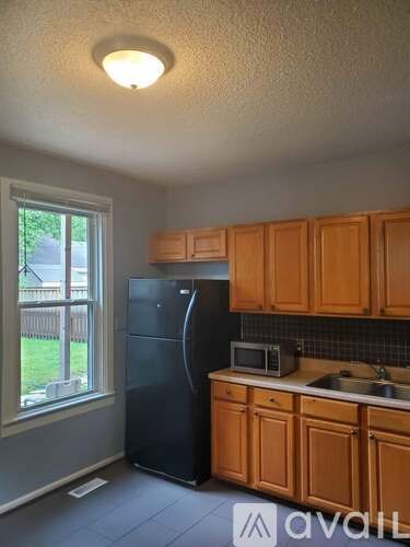A kitchen with wooden cabinets and a black refrigerator.