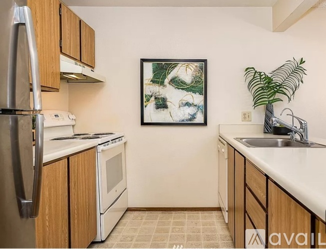 A kitchen with wooden cabinets and a fridge on the left.