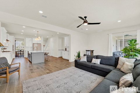 A living room with a grey couch and a ceiling fan.