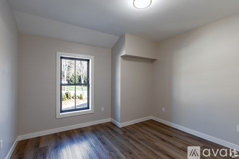 A room with a window and wooden flooring.