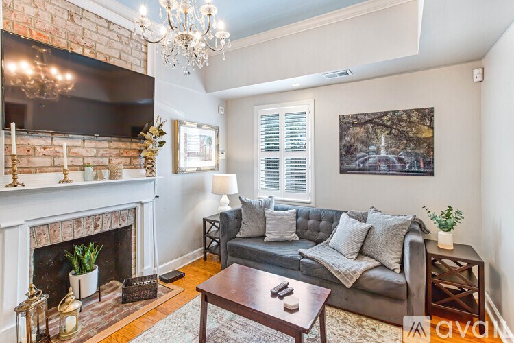 A living room with a grey couch, a fireplace, and a chandelier.