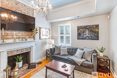 A living room with a grey couch, a fireplace, and a chandelier.