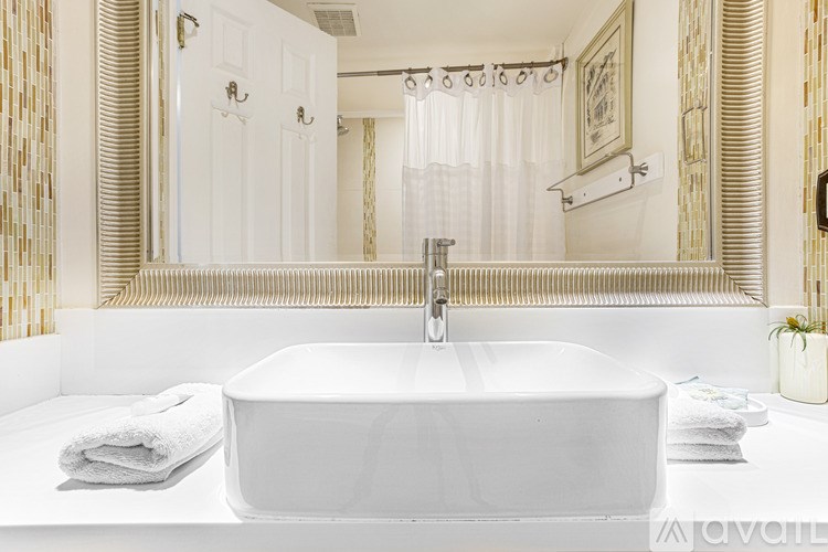 A white sink in a bathroom with a mirror above it.