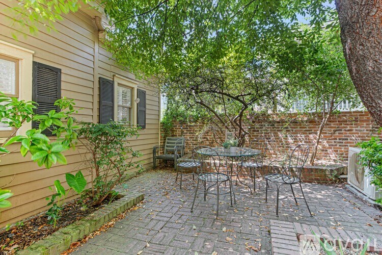 A patio with a table and chairs is surrounded by a brick wall and trees.