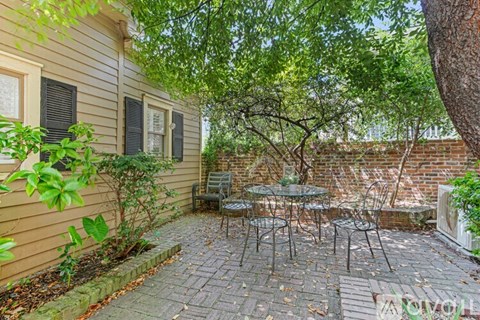 A patio with a table and chairs is surrounded by a brick wall and trees.