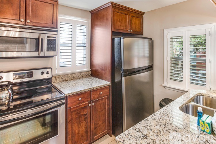 A kitchen with a stove, microwave, refrigerator, and sink.