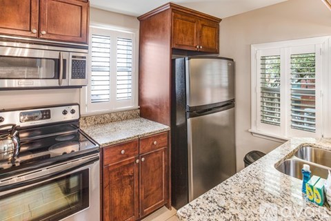 A kitchen with a stove, microwave, refrigerator, and sink.
