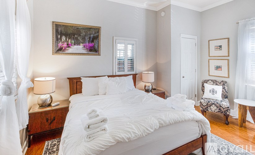 A bedroom with a large bed and a painting on the wall.