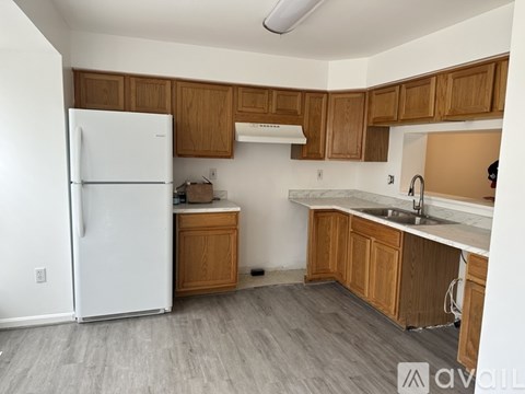 A kitchen with a white fridge and wooden cabinets.