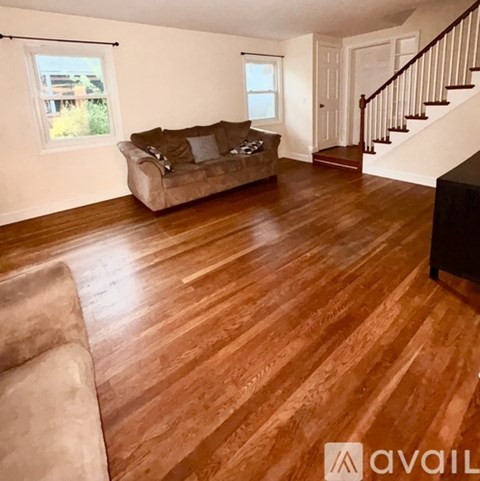 A living room with a brown couch and wooden floors.