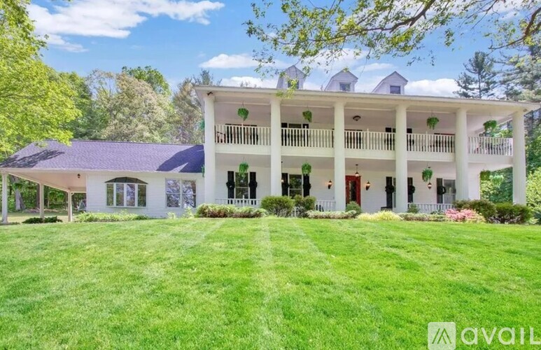 A large white house with a balcony and a green lawn in front.