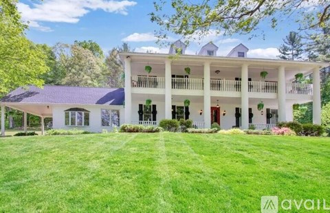 A large white house with a balcony and a green lawn in front.