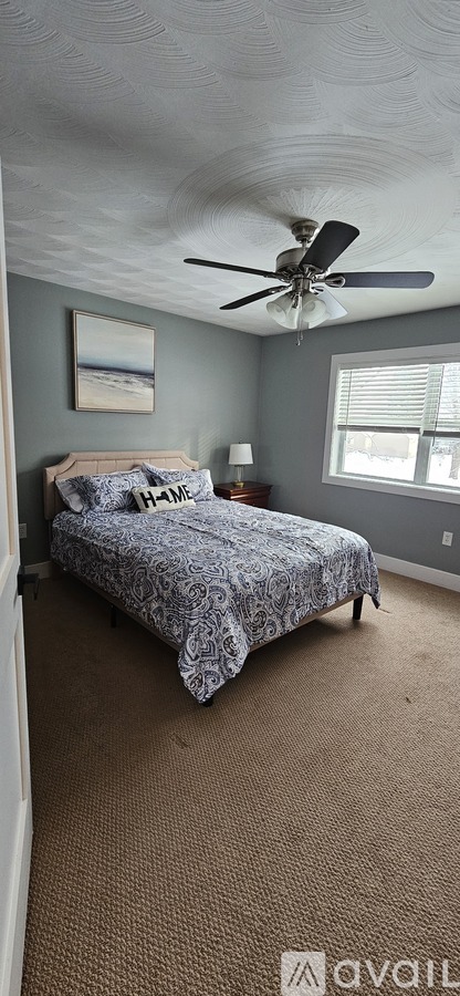 A bedroom with a bed and a ceiling fan.