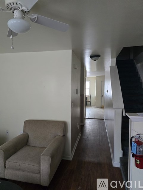 A living room with a beige couch and a white ceiling fan.