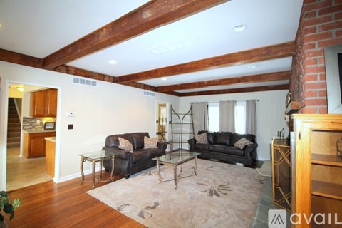 A living room with a black couch and a glass table.