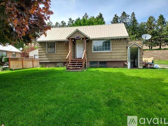 A house with a brown roof and a green lawn in front.