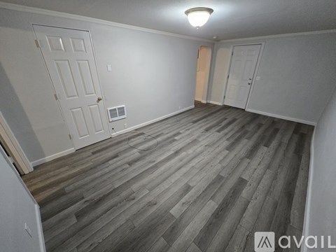 A room with wooden flooring and two doors.