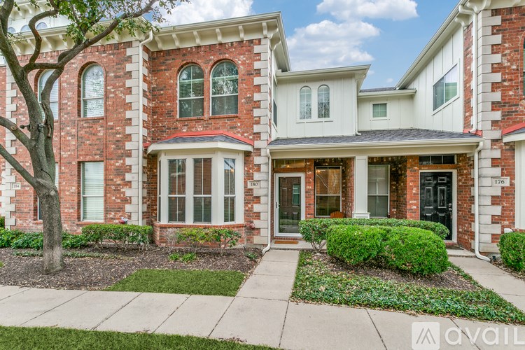 A red brick house with a tree in front.