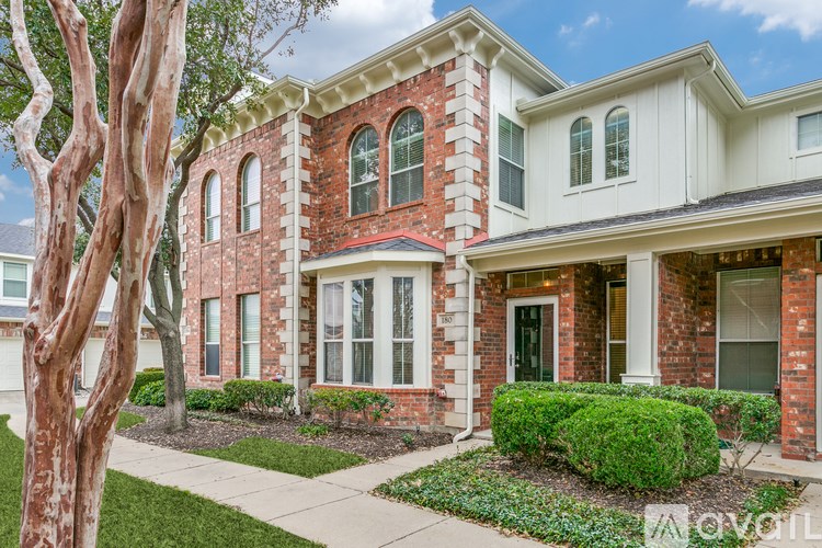 A red brick house with white trim and a large tree in front.