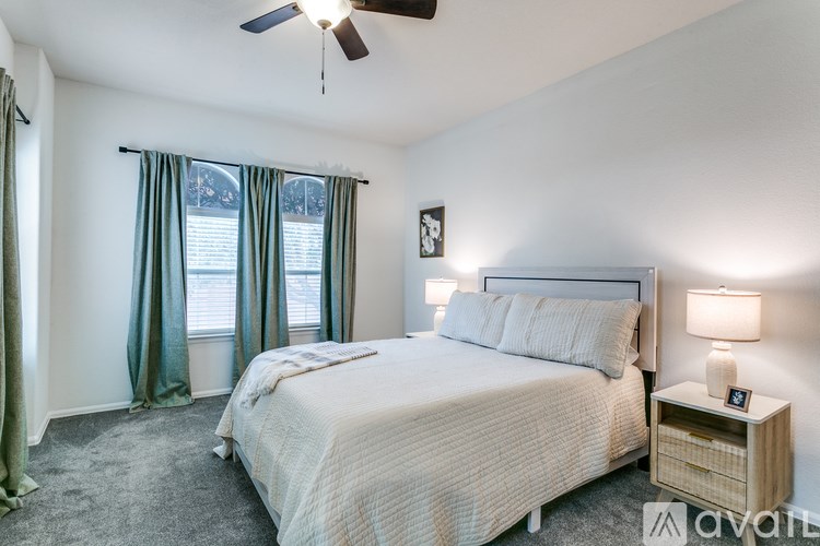 A bedroom with a large bed and a ceiling fan.