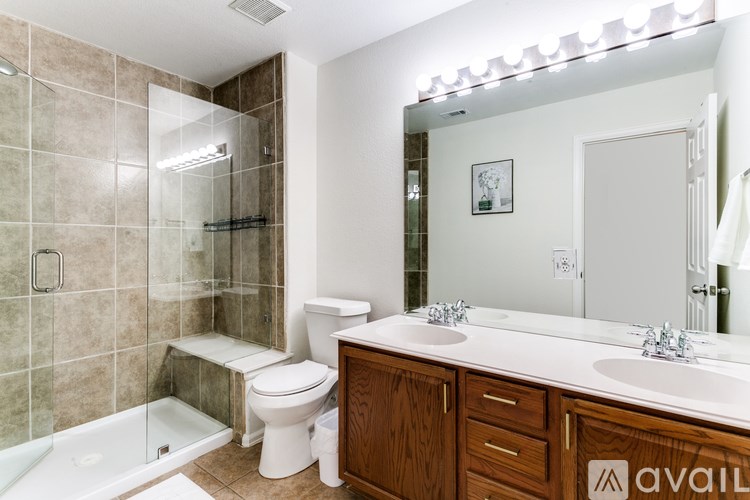 A bathroom with a white toilet, a white sink, and a glass shower stall.