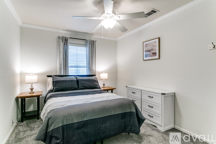 A bedroom with a bed, nightstands, and a ceiling fan.
