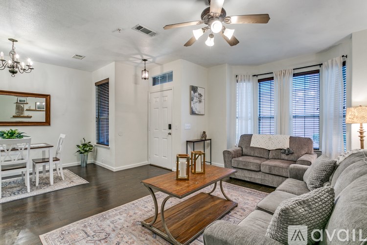 A living room with a grey couch, a wooden coffee table, and a white dining table.
