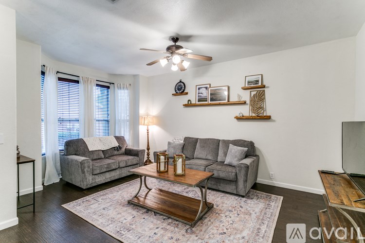 A living room with a grey couch, a wooden coffee table, and a ceiling fan.