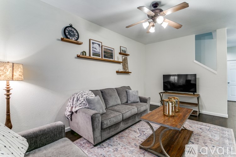 A living room with a grey couch, a wooden coffee table, and a ceiling fan.