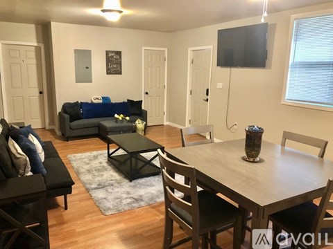 A living room with a couch, chairs, and a television.