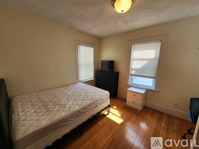 A room with wooden floors and a window with blinds.
