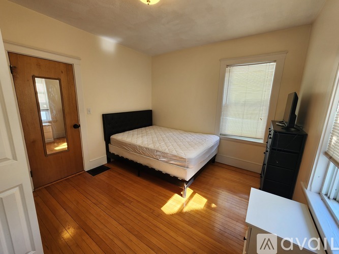 A room with wooden floors and a window with blinds.
