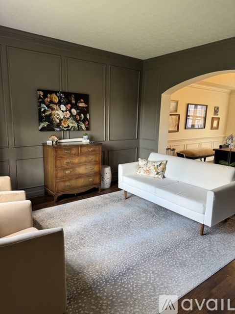 A living room with a white couch and a wooden cabinet.