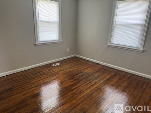 A room with wooden floors and two windows.