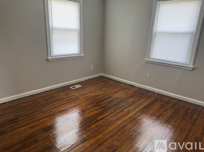 A room with wooden floors and two windows.