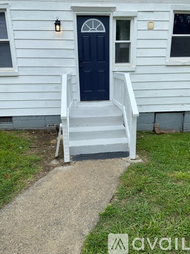 A white house with a dark blue door and a white porch.