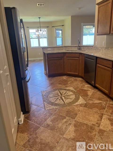 A kitchen with a tile floor and a black refrigerator.