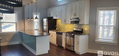 A kitchen with a black refrigerator and a stove top oven.