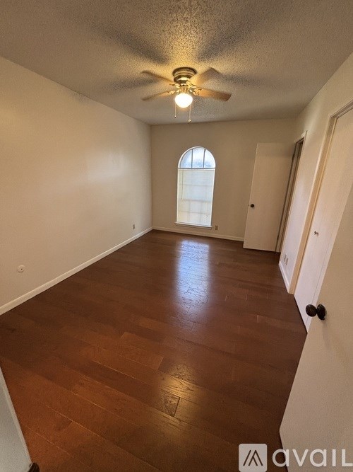 A room with wooden flooring and a ceiling fan.